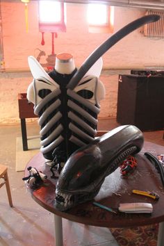 a table topped with a black and white alien head sitting on top of a wooden table