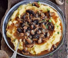 mashed potatoes with mushrooms and gravy in a bowl on a wooden table