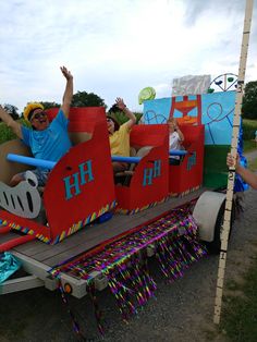 some people are riding in a fake train on the road with balloons and streamers