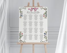 an easel with a wedding seating chart on it in front of a white curtain