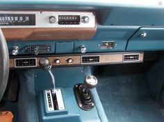 the interior of an old car with blue leather and wood trim, including radio controls