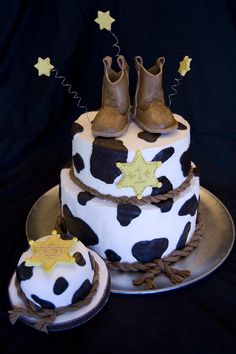 a birthday cake decorated with cow print and gold stars on it's top, next to a pair of cowboy boots