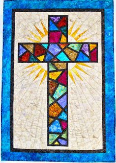 a quilted wall hanging with a cross and sunbursts on it's side