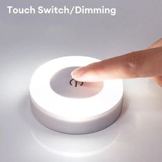 a person touching the touch switch / dimming button on a white surface