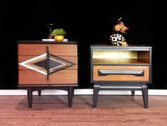 two nightstands side by side on top of a hard wood floor with black walls in the background