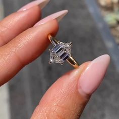 a woman's hand holding an engagement ring with two diamonds on the top and side