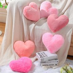 four pink heart shaped pillows sitting on top of a bed next to a white blanket