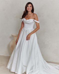 a woman in a white wedding dress posing for the camera with her hands on her hips