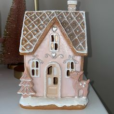 a pink and white gingerbread house on a table