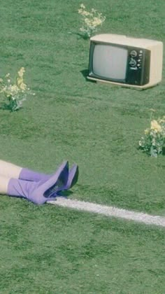 a person laying on the ground in front of an old tv and a television set