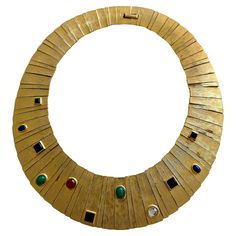 This exquisite vintage Les Bernard cabochon collar necklace is a striking example of the brand's iconic designs from the 1960s-1980s. Crafted with a bold and elegant pale gold-tone finish, the necklace features a series of multi-colored cabochon imitation stones, designed to mimic lapis, onyx, carnelian, and malachite, meticulously set in a radiant collar style, embodying an Egyptian Revival motif. Size: Approximately 14.5" inner circumference. The width varies across the design from 3/4" wide a Gold Collar Necklace, Vintage Choker Necklace, Choker Collar Necklace, Statement Collar Necklace, Black Choker Necklace, Vintage Choker, Egyptian Revival, Black Choker, Gold Choker