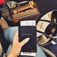 a person sitting on the ground holding a passport in their hand and luggage behind them