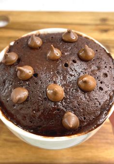 a chocolate cake in a white bowl on a wooden table