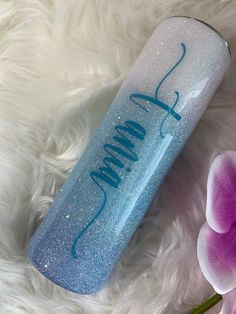 a blue and white water bottle sitting on top of a fur covered floor next to a purple flower