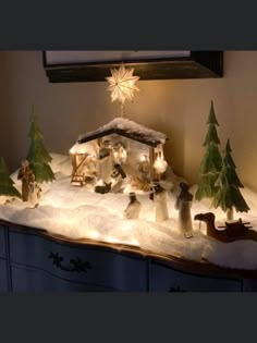 a lighted christmas scene on top of a dresser