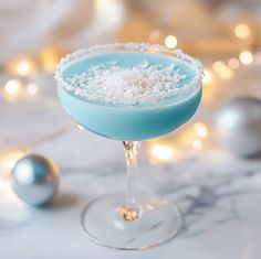 a blue cocktail with white sugar on the rim and garnished in coconut flakes