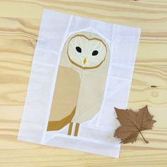 an owl is sitting on top of a piece of paper next to a maple leaf