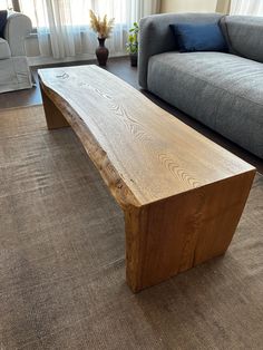 a wooden bench sitting in the middle of a living room next to a gray couch