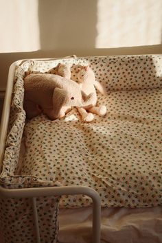 a teddy bear is laying in a crib