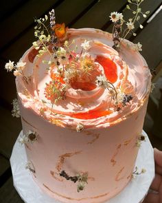 a pink frosted cake with flowers on top