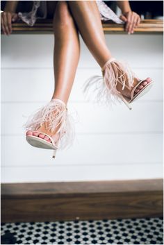 a woman's legs and shoes are shown in the air with feathers on them