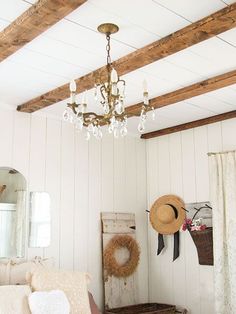 a living room filled with furniture and a chandelier hanging from a wooden beam