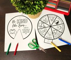 two coloring pages with scissors and crayons on a table next to a potted plant