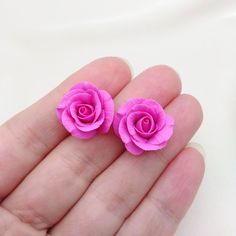 two tiny pink roses are in the palm of someone's hand on a white background