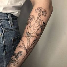 a woman's arm with flowers and leaves tattooed on the left side of her arm