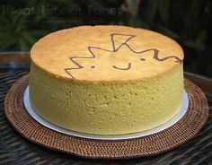 a yellow cake sitting on top of a white plate next to a wooden table with writing on it