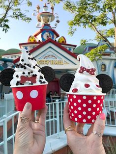 two people holding up mickey and minnie mouse cupcakes