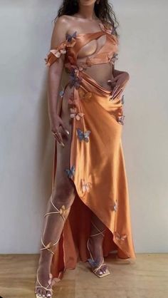 a woman in an orange dress with butterflies on her body and one hand on her hip