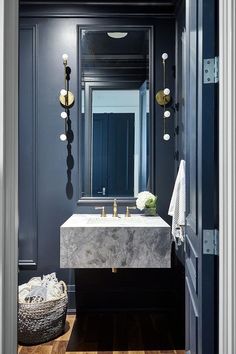 a bathroom with blue walls and marble counter top, along with an open door that leads to another room