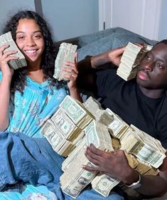 a man and woman sitting on a couch holding stacks of money