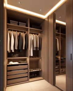 a walk in closet with clothes hanging on the walls and drawers, along with an illuminated ceiling