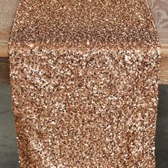 a gold sequin table runner on top of a wooden table with a wood background