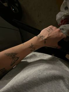 a person with a tattoo on their arm is sitting in a chair and holding onto the arm of another person