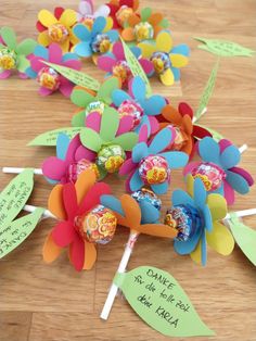 some candy lollipops are laying on a table with paper flowers and leaves