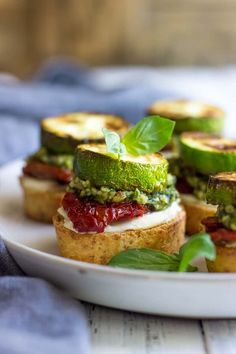 small sandwiches with cucumbers and other toppings on a white plate, ready to be eaten