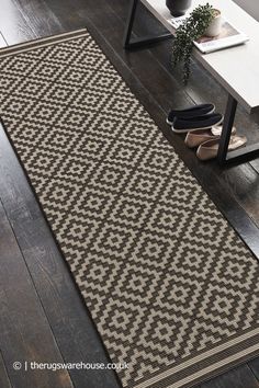 a large rug on the floor in a living room with a coffee table and plant