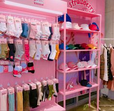 a pink shelf filled with lots of baby clothes and hats on it's shelves