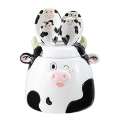 a ceramic cow container with three little cows sitting on it's back and one is black and white