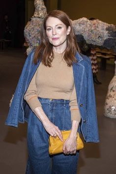 a woman standing in front of sculptures holding a yellow purse and looking at the camera