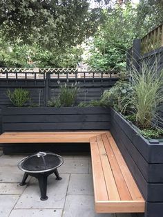 a wooden bench sitting on top of a stone floor next to a black planter