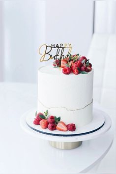 a white cake topped with strawberries and a happy birthday sign