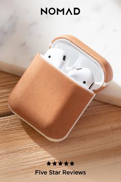 an apple airpods case sitting on top of a wooden table with the words nomad above it