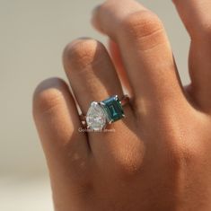 a woman's hand with a ring on it and an emerald stone in the middle