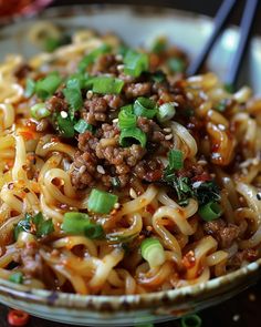 a bowl full of noodles with meat and green onions on top, ready to be eaten