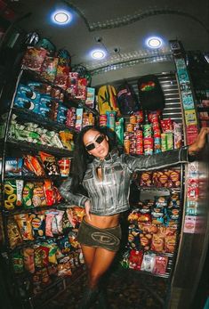 a woman standing in front of a store filled with lots of food and candy bars