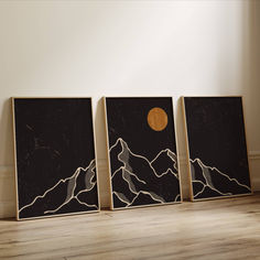 three black and white paintings sitting on top of a wooden floor